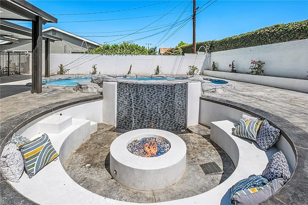 Sunken fire-pit lounge with a tiled water wall in daylight