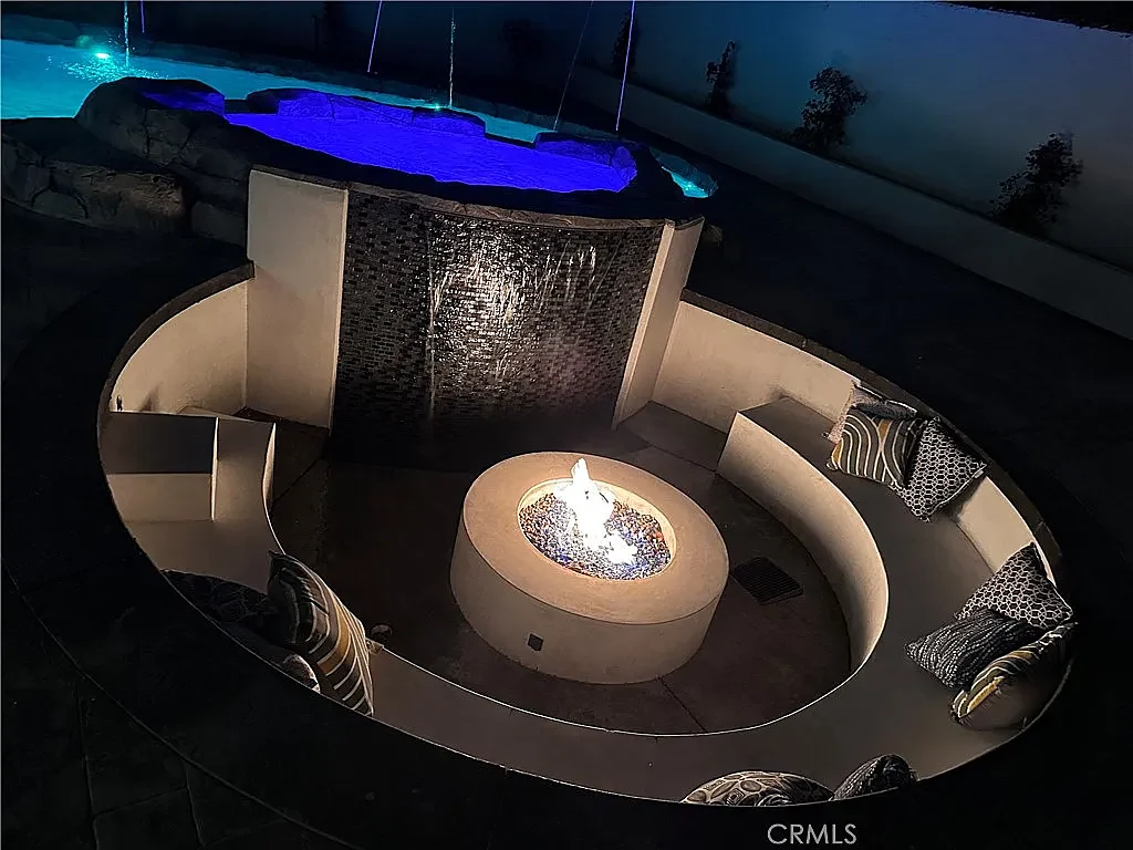 The sunken fire-pit lounge at night with the fire lit