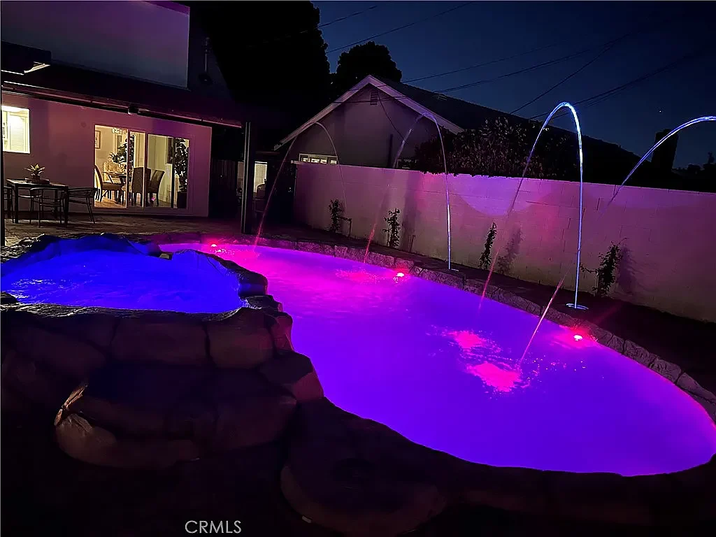 The same pool lit in magenta at night, deck jets running