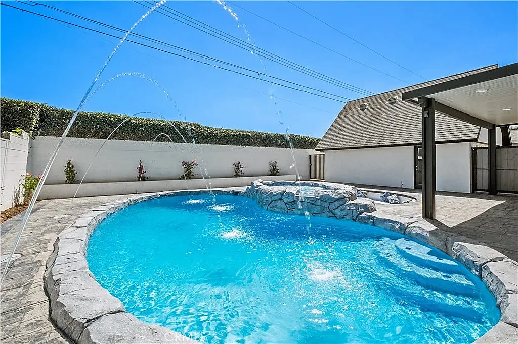 Free-form pool with arcing deck jets in daylight